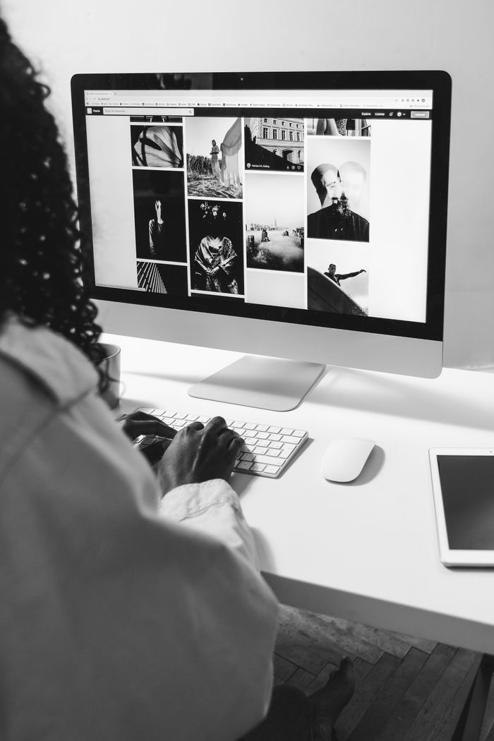 home-img Black and white of crop anonymous African American female working with computer at table with tablet